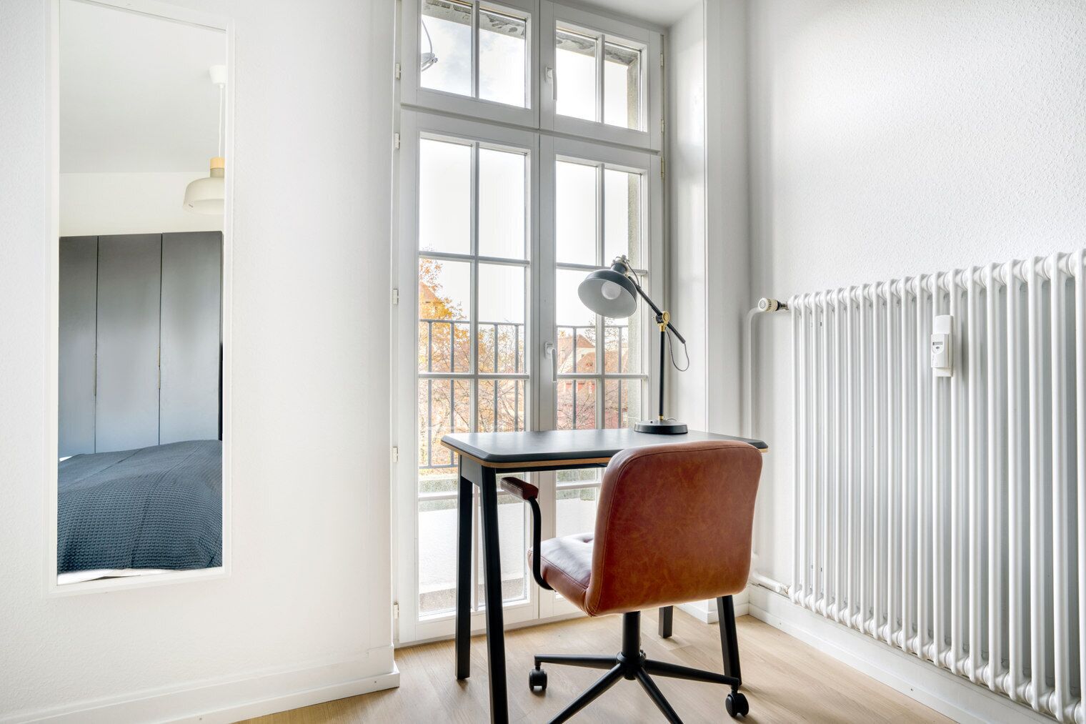 Una habitación con escritorio, silla y radiador.