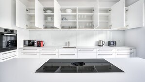 A modern kitchen with white cabinetry, a black induction cooktop, and stainless steel appliances. - Airy Vorstädte 3.5 Room w/ W/D & Storage, 2 min to Market, by Blueground (Basel)