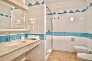 A bathroom with a sink, mirror, towel rack, shower, and toilet.