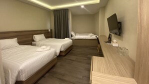 Habitación de hotel con dos camas, un escritorio, un televisor y una ventana con cortinas.