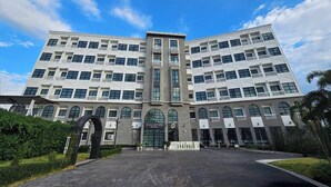 Un hotel moderno con fachada simétrica, varios balcones y una entrada central.
