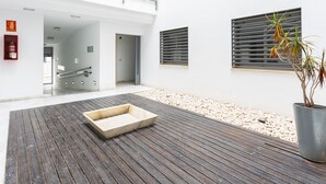 Un interior moderno con una terraza de madera, una maceta con una planta y un extintor en la pared.
