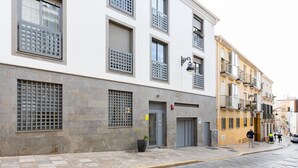 Un edificio de fachada de piedra, con varias ventanas de rejas y una entrada en la planta baja.