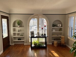 Relax in this serene space with a large arched window, central table, and comfortable seating.