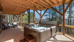 Eine Holzterrasse mit Whirlpool, Liegestühlen und einem Tisch.