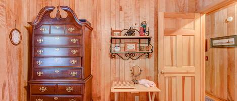 A wooden-paneled room with a large wooden dresser, a small table with a mirror, and a door.