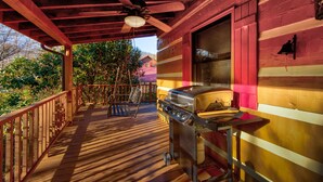 Eine überdachte Veranda mit Grill, Holzwertlauf und Deckenventilator.