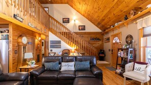 A cozy cabin interior with a wooden staircase, leather furniture, and various decorations. - Country Life - hot tub, wood burning fireplace, pet friendly (Vilas)