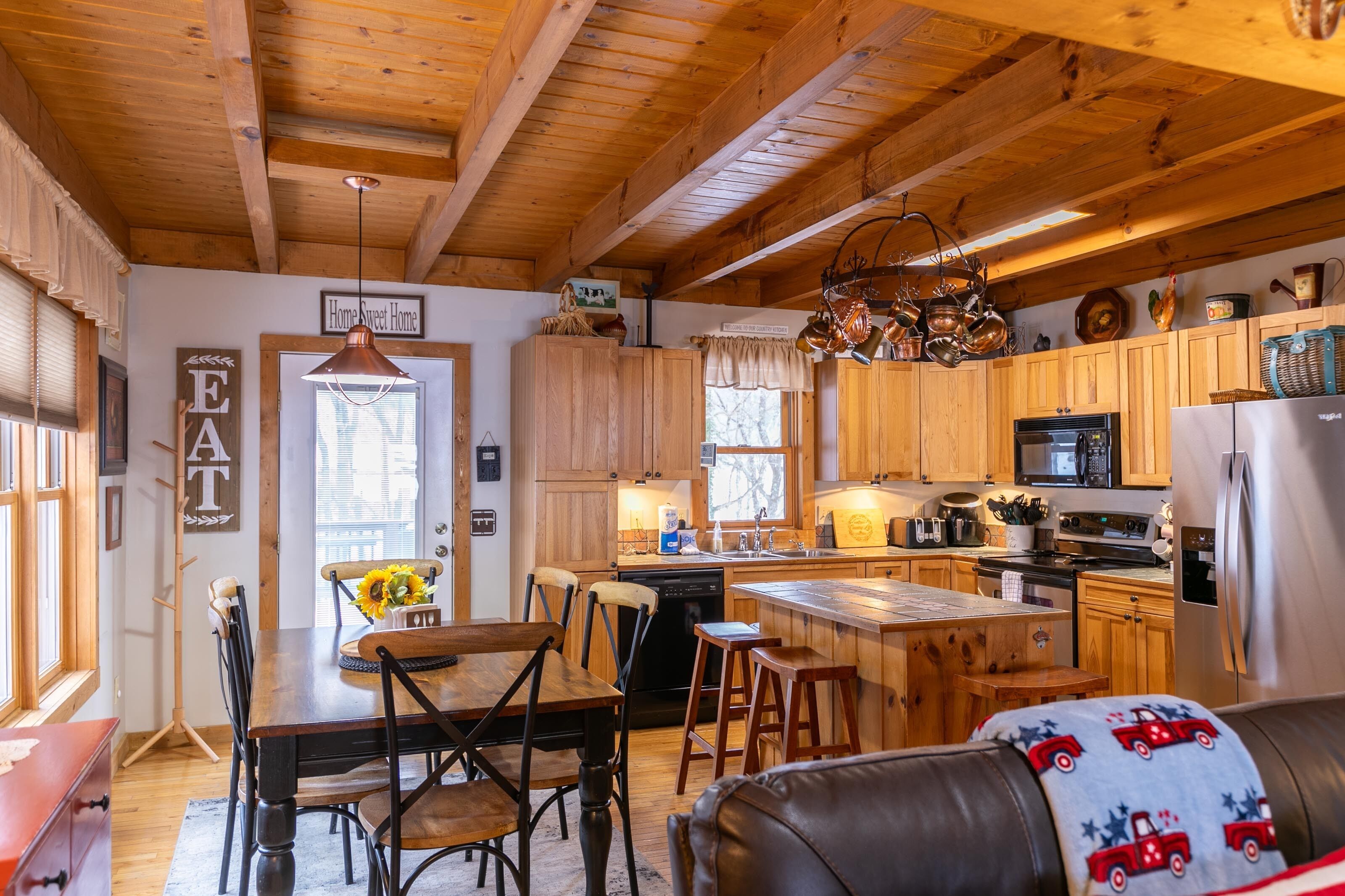 Una cocina acogedora con armarios de madera, una isla central y un comedor con mesa y sillas.