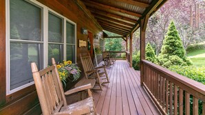 A wooden porch with rocking chairs and a view of a well-maintained garden. - Country Life - hot tub, wood burning fireplace, pet friendly (Vilas)