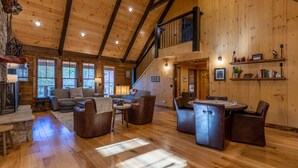 A spacious log cabin interior with a high ceiling, a staircase to an upper level, and a cozy seating area with a fireplace. - Papa's View - Pet Friendly Luxury Log Cabin in Valle Crucis with Views and Hot Tub! (Banner Elk)