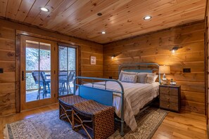 Ein Schlafzimmer einer Holzhütte mit einem Bett, einem Schreibtisch und einem Stuhl.