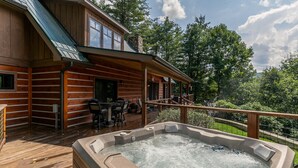 A wooden cabin with a hot tub on the deck, surrounded by trees. - Papa's View - Pet Friendly Luxury Log Cabin in Valle Crucis with Views and Hot Tub! (Banner Elk)
