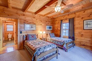 Ein Schlafzimmer einer Holzhütte mit zwei Betten, einem Deckenventilator und gerahmten Bildern an den Wänden.
