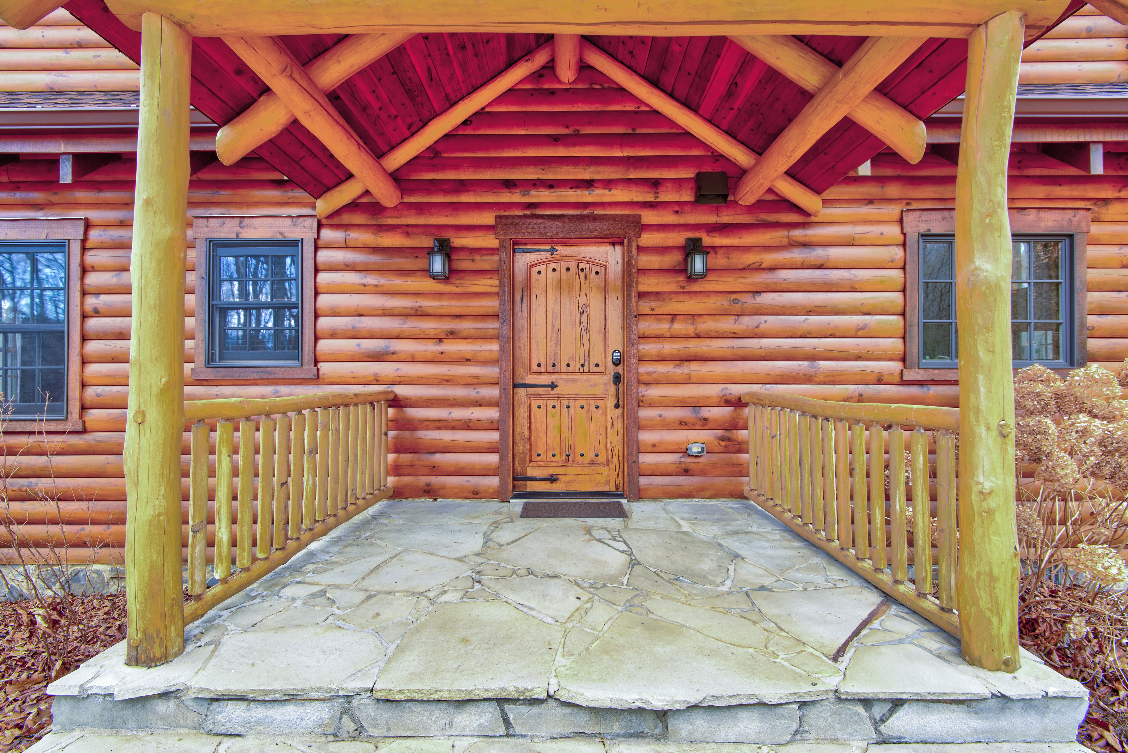 A log cabin with a stone-paved porch and a wooden door.