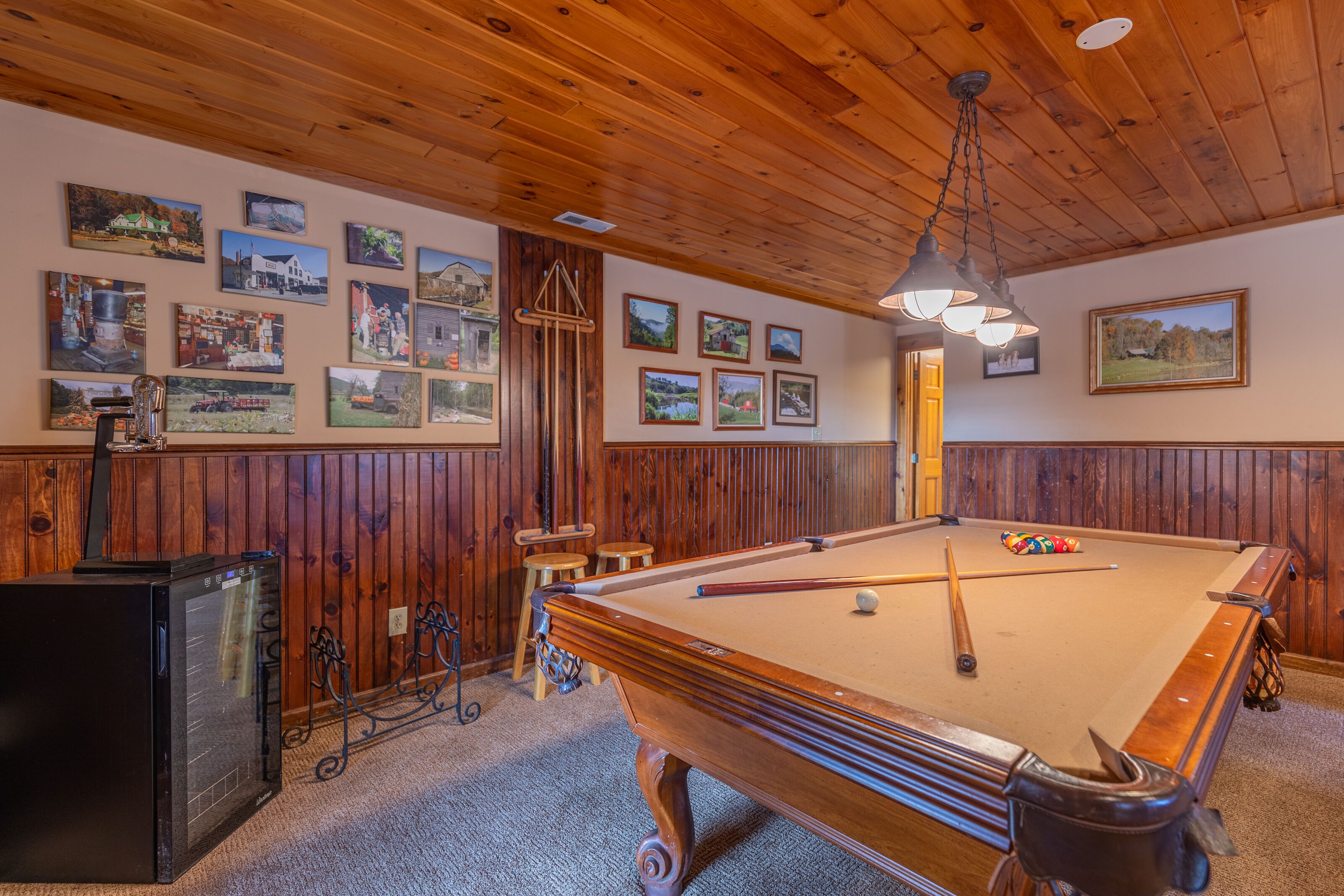 Une table de billard avec un cadre en bois, une queue de billard et une bille de billard. Les murs sont en bois et le plafond est orné de poutres en bois.
