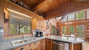 Una cocina amplia con encimeras de granito, gabinetes de madera y lavavajillas integrado.