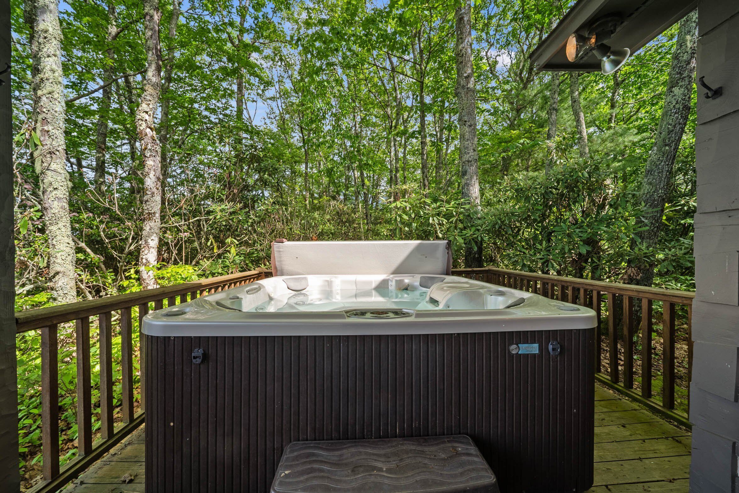 Un bain à remous sur une terrasse en bois, entouré d’une végétation luxuriante.