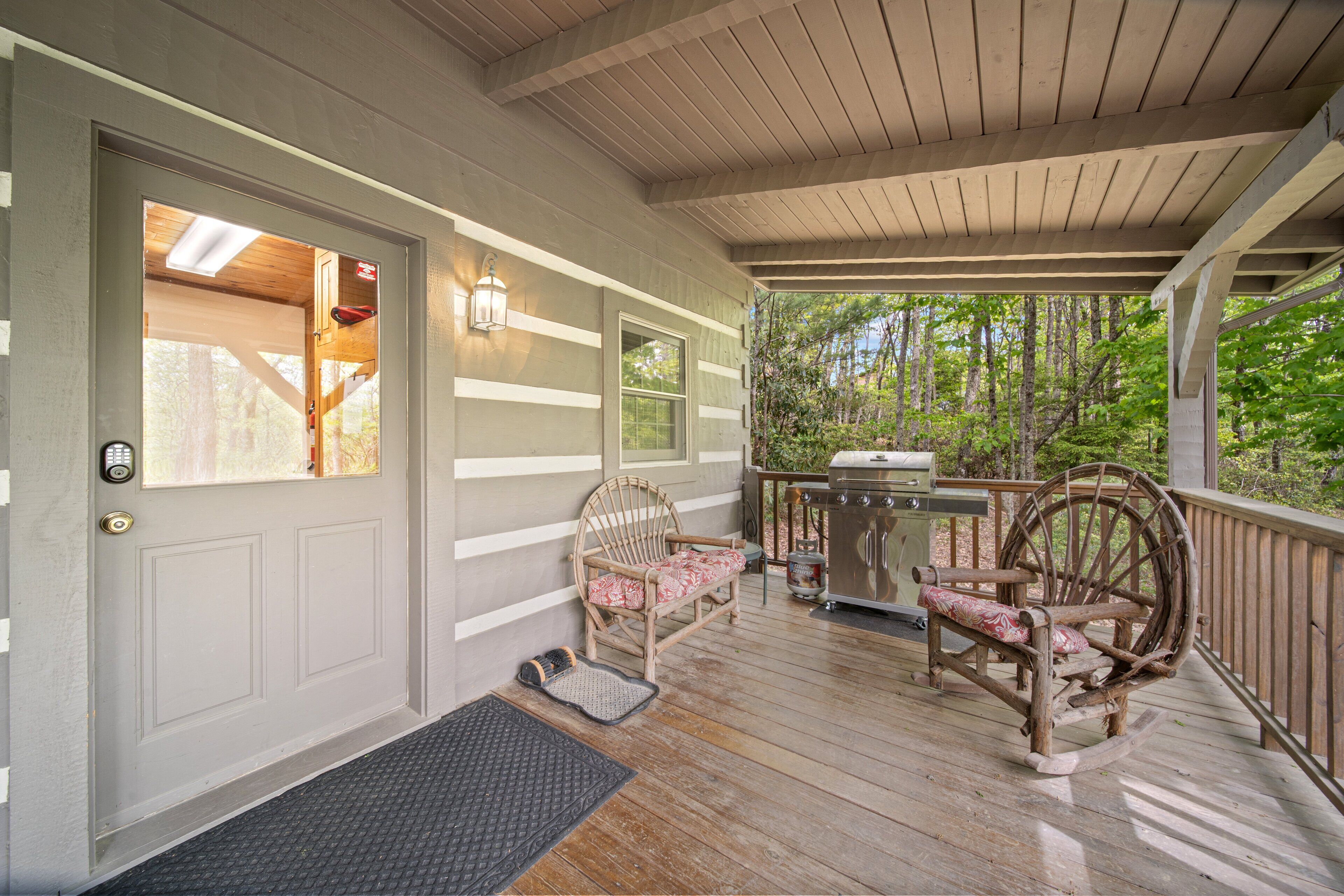 A covered porch with a wooden bench, a grill, and a door with a keypad lock.