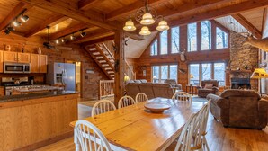 Amplia cabaña de troncos con comedor de madera, cocina y sala de estar.