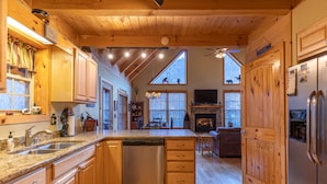 A spacious kitchen with wooden cabinets, a dishwasher, and a large island. - Bear Creek - Beautiful home with gas fireplace, custom wood burning firepit, shuffleboard, and more! (Sugar Grove)