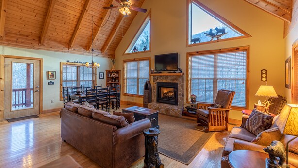 A spacious living room with a fireplace, wooden ceiling, and large windows. - Bear Creek - Beautiful home with gas fireplace, custom wood burning firepit, shuffleboard, and more! (Sugar Grove)
