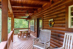 A wooden cabin with a porch, a table, and chairs. - Bear Creek - Beautiful home with gas fireplace, custom wood burning firepit, shuffleboard, and more! (Sugar Grove)