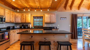 Una cocina con armarios de madera, una isla central con taburetes y vistas al exterior a través de una ventana.