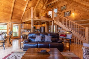 Un intérieur de cabine spacieux, avec un escalier en bois, un canapé en cuir et un coin repas.