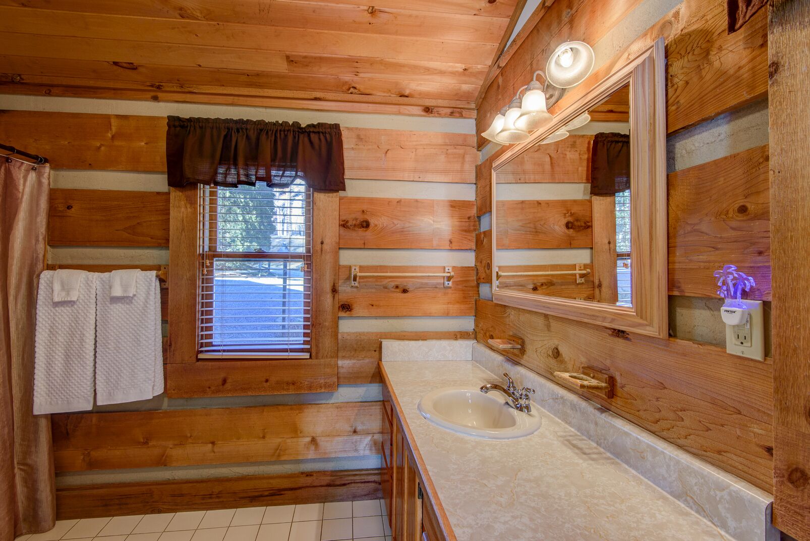 Rustic log walls and warm wood tones give this full bath at Fox's Lair a cozy cabin feel.