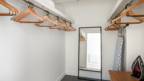A walk-in closet with wooden hangers, a large mirror, and a radiator. - Deluxe Marylebone 2BR nr Oxford St, by Blueground (London)