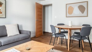 A modern living room with a grey sofa, a wooden coffee table, and a dining area with a round table and four chairs. - Deluxe Marylebone 2BR nr Oxford St, by Blueground (London)