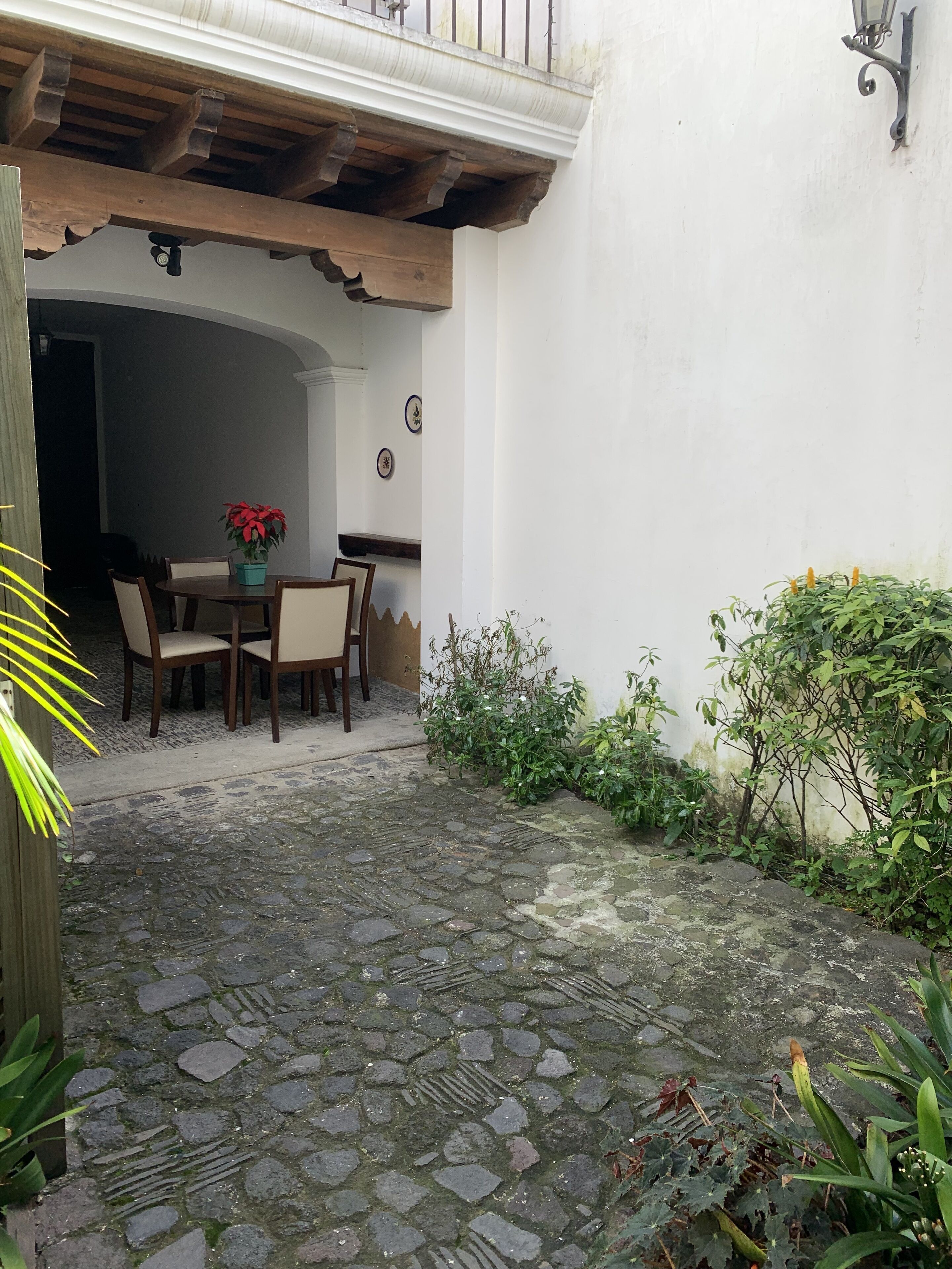 Un cortile con un vialetto in pietra, un tavolo di legno con sedie e piante in vaso.