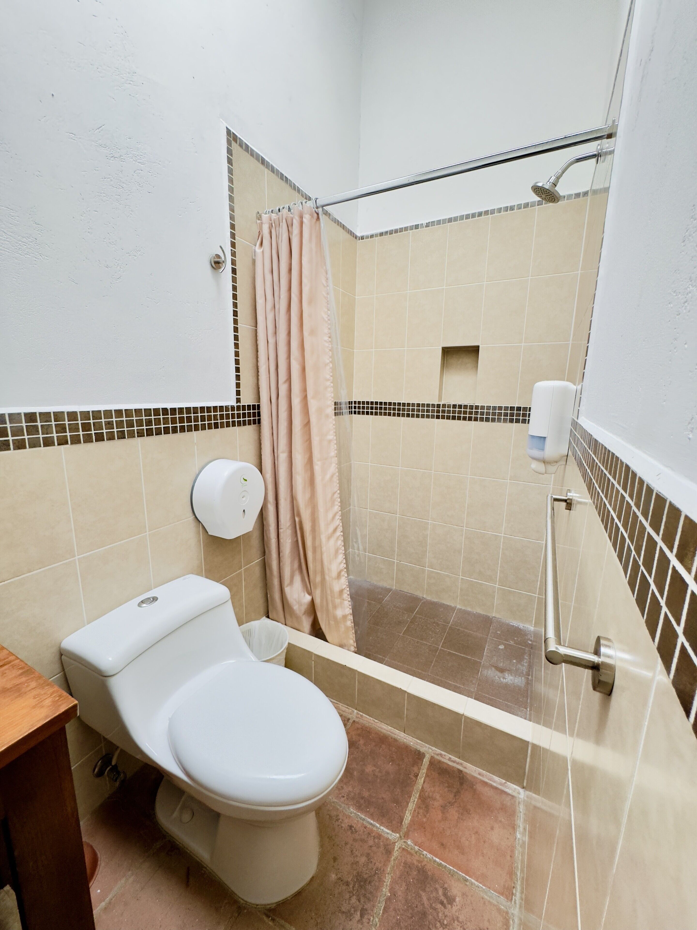 Ein Badezimmer mit Toilette, Dusche und einem Händetrockner.