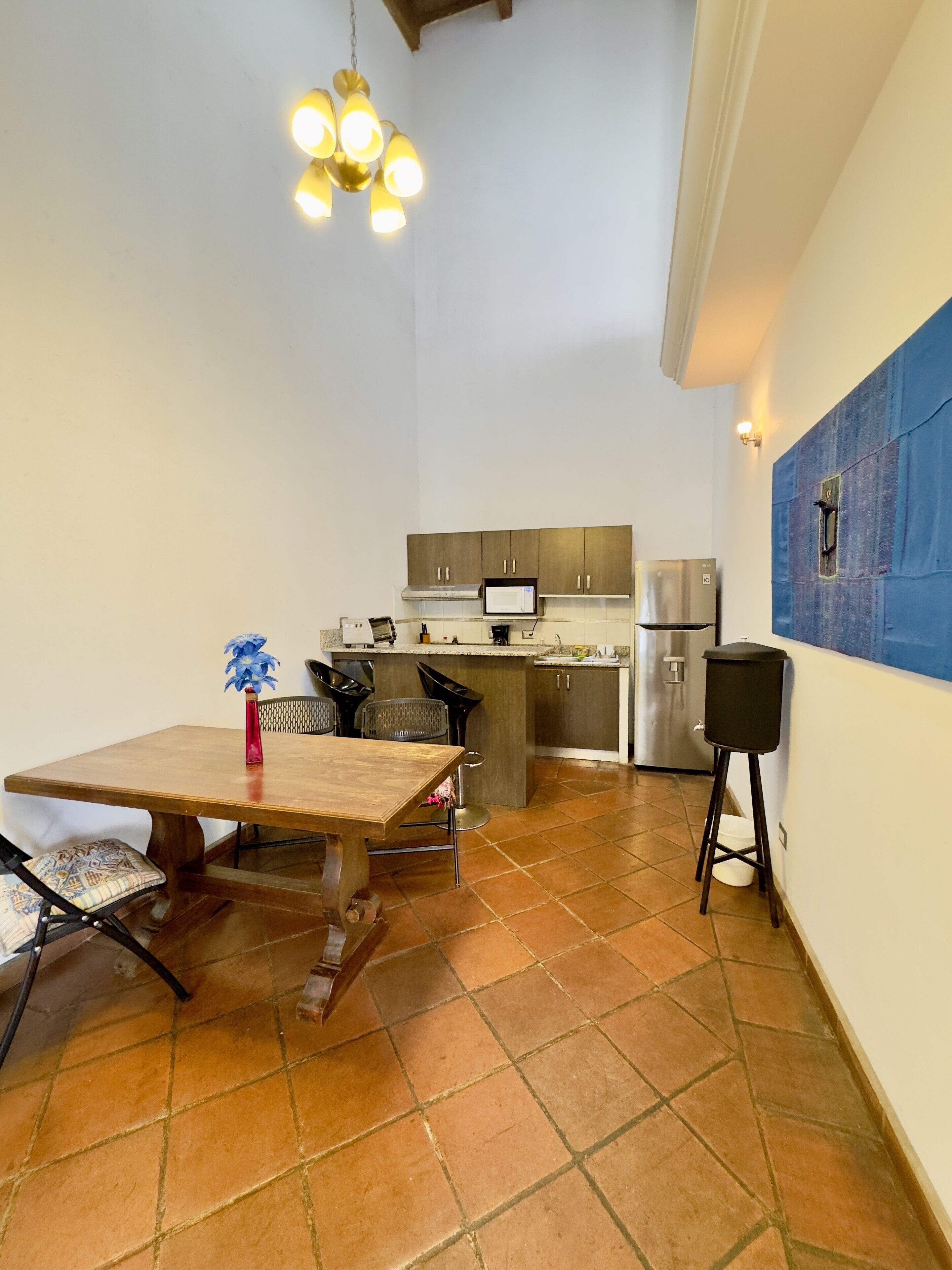 Una cocina compacta con comedor, que incluye una mesa y sillas de madera, una pequeña isla y electrodomésticos modernos.
