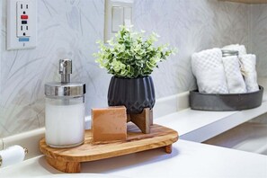 Un mueble de baño con dispensador de jabón, una pastilla de jabón y una planta en maceta.