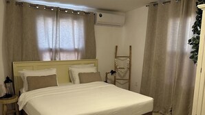 Un lit bien fait, avec une literie blanche et marron, une lampe de chevet et une échelle en bois appuyée contre le mur.