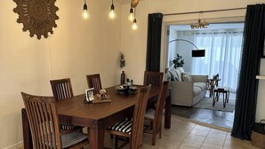 Un coin repas avec une table et des chaises en bois, un élément décoratif mural et un luminaire moderne.