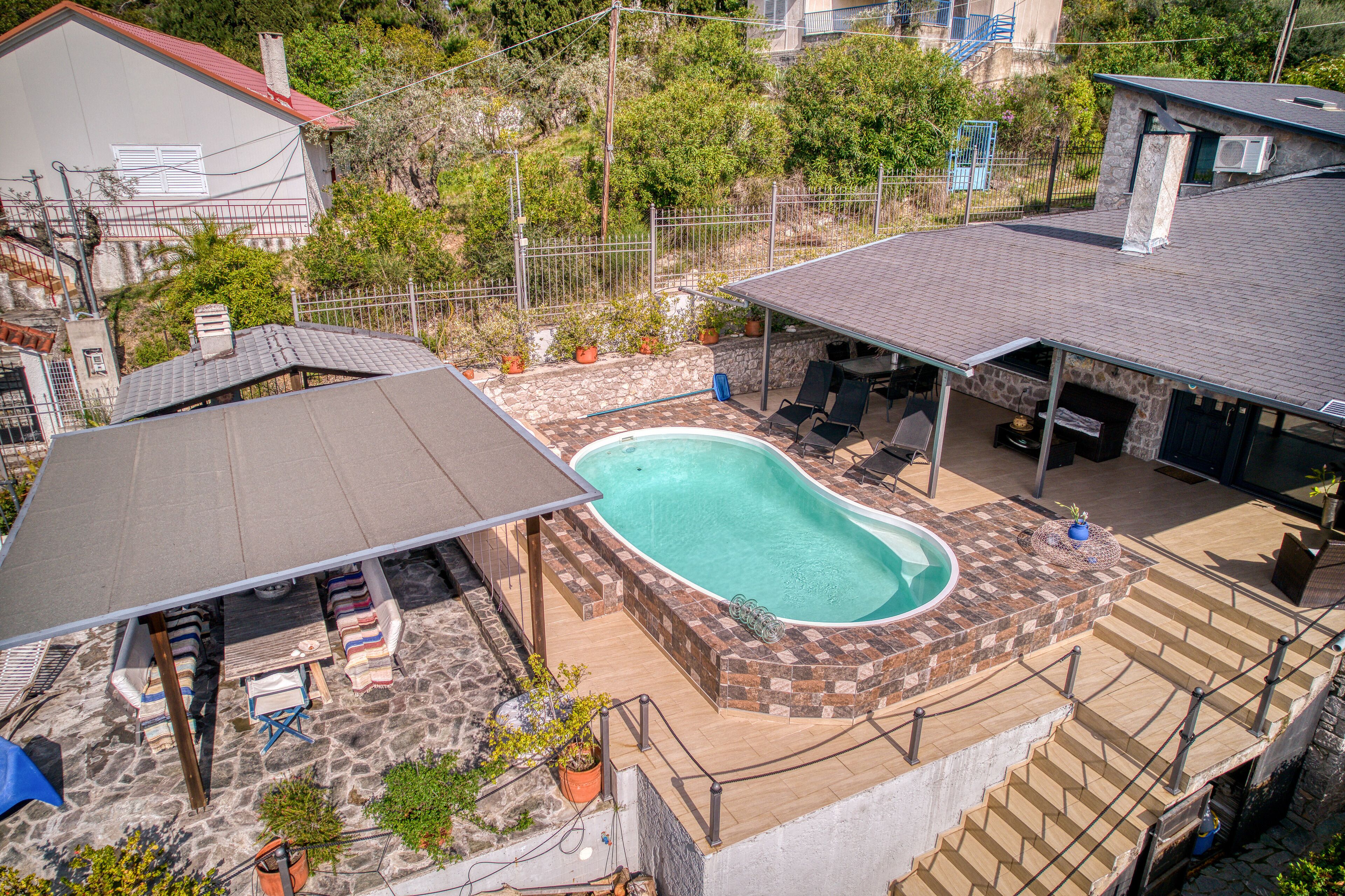 En bostadsfastighet med en swimmingpool, utomhusmöbler och en stenbelagd uteplats.