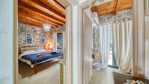 Un dormitorio con pared de piedra, techo de madera, cama con manta azul y un candelabro.