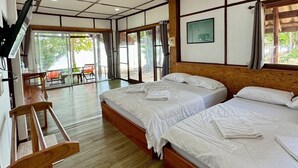 Een hotelkamer met twee bedden, een houten vloer, een televisie en uitzicht op de omgeving.