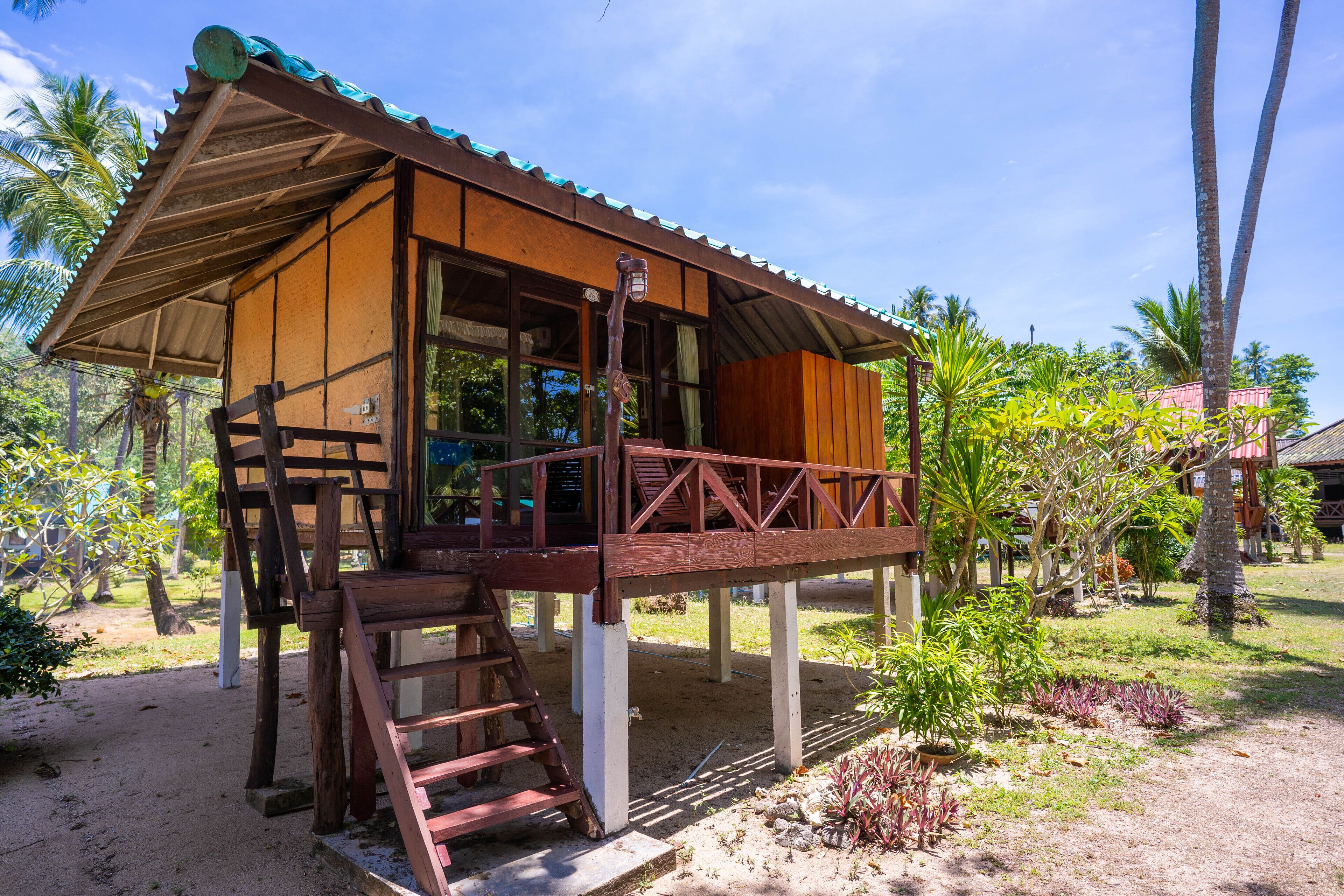 A wooden structure with a balcony, a ladder, and a small garden area.