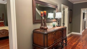A hallway with a wooden dresser, two candles, a mirror, and a lamp. - Youngsville Retreat- pool, private pond, outdoor fireplace  (Broussard)