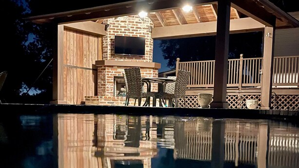 A pool with a wooden deck and a brick fireplace. - Youngsville Retreat- pool, private pond, outdoor fireplace  (Broussard)