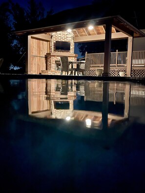 A pool with a wooden deck and a brick fireplace. - Youngsville Retreat- pool, private pond, outdoor fireplace  (Broussard)