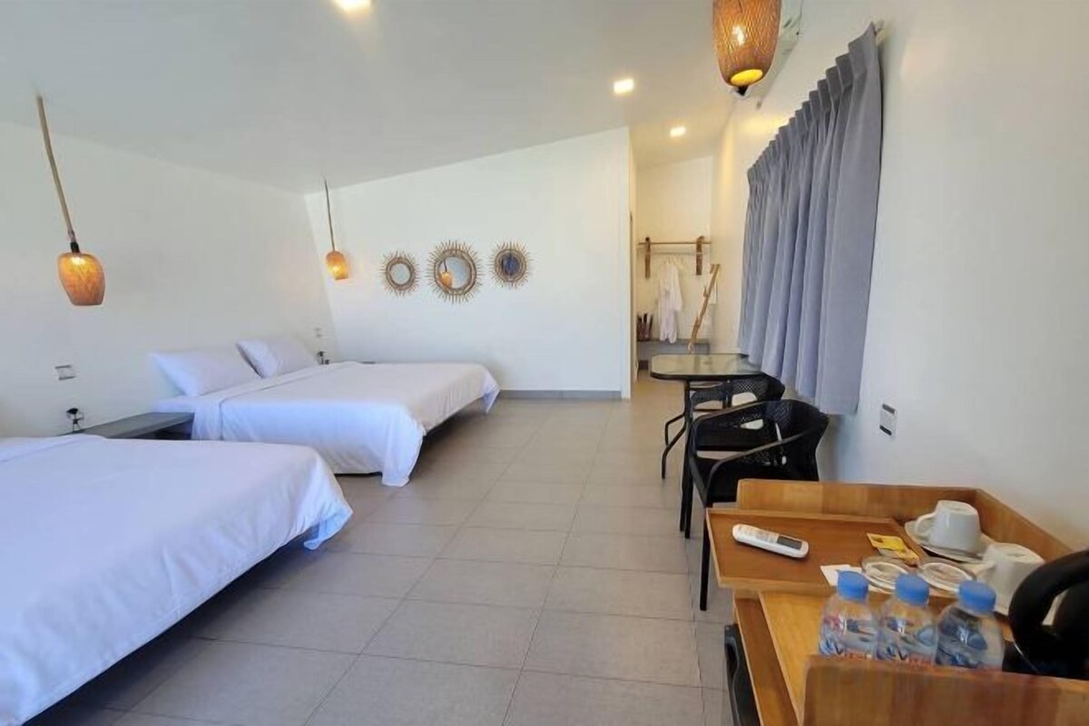 A hotel room with two beds, a desk with a chair, a table with a tray of items, and a wall with decorative plates.
