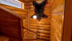 Ein rustikales Blockhaus-Interieur mit einem Fellteppich, Holzwänden und einem Fenster.