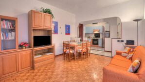 A living room with a TV, wooden cabinets, a dining table, and a sofa. - Casa Letizia few min from sea outdoor dining for 4, Sanremo, Italy (Sanremo)