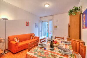 Een eethoek met een tafel voor vier personen, een bank en een houten kast.