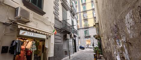 A narrow street with a boutique store named 'SD Blossoms' on the left, featuring mannequins displaying clothing.